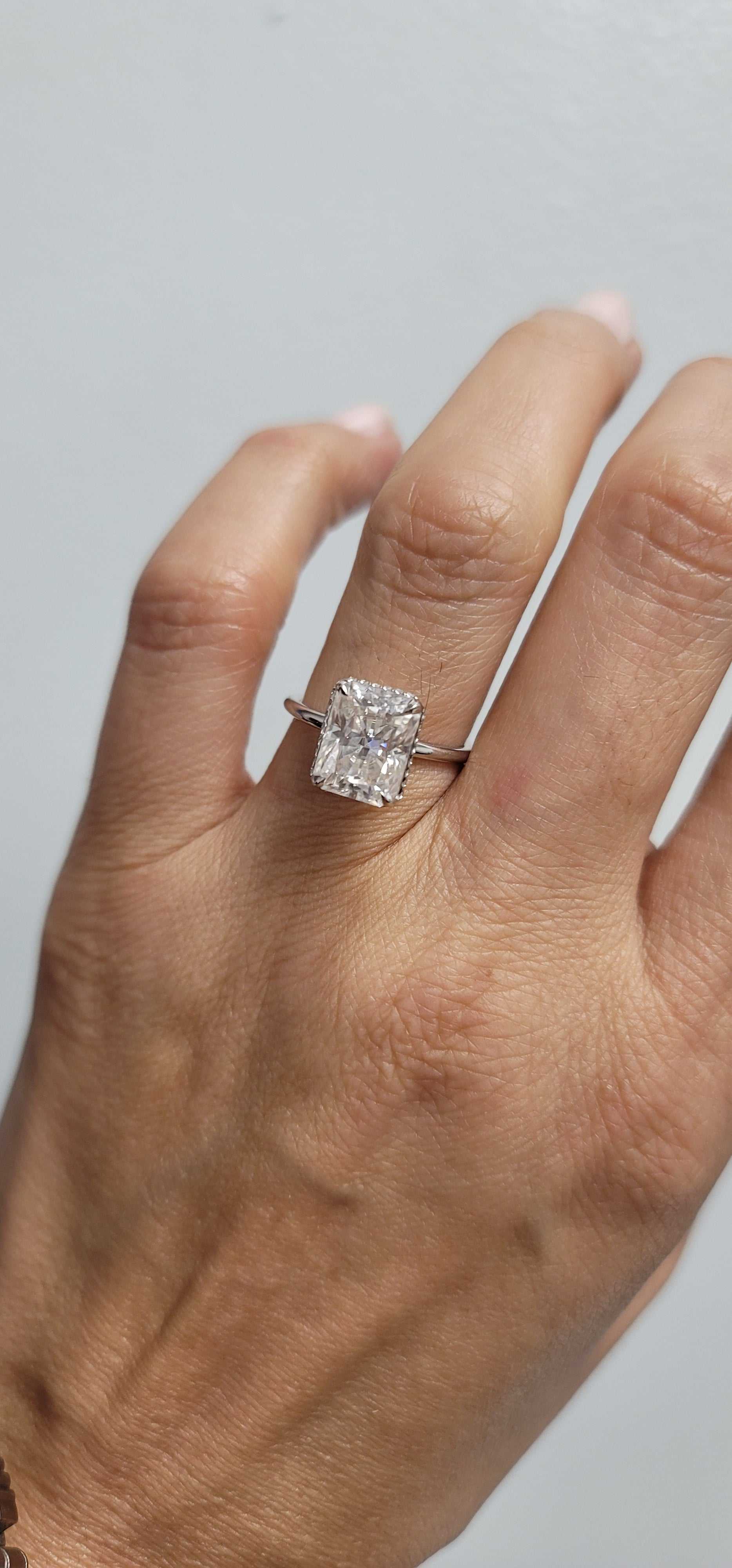 Mimi Hidden Halo Engagement Ring with radiant cut diamond and hidden halo setting on finger