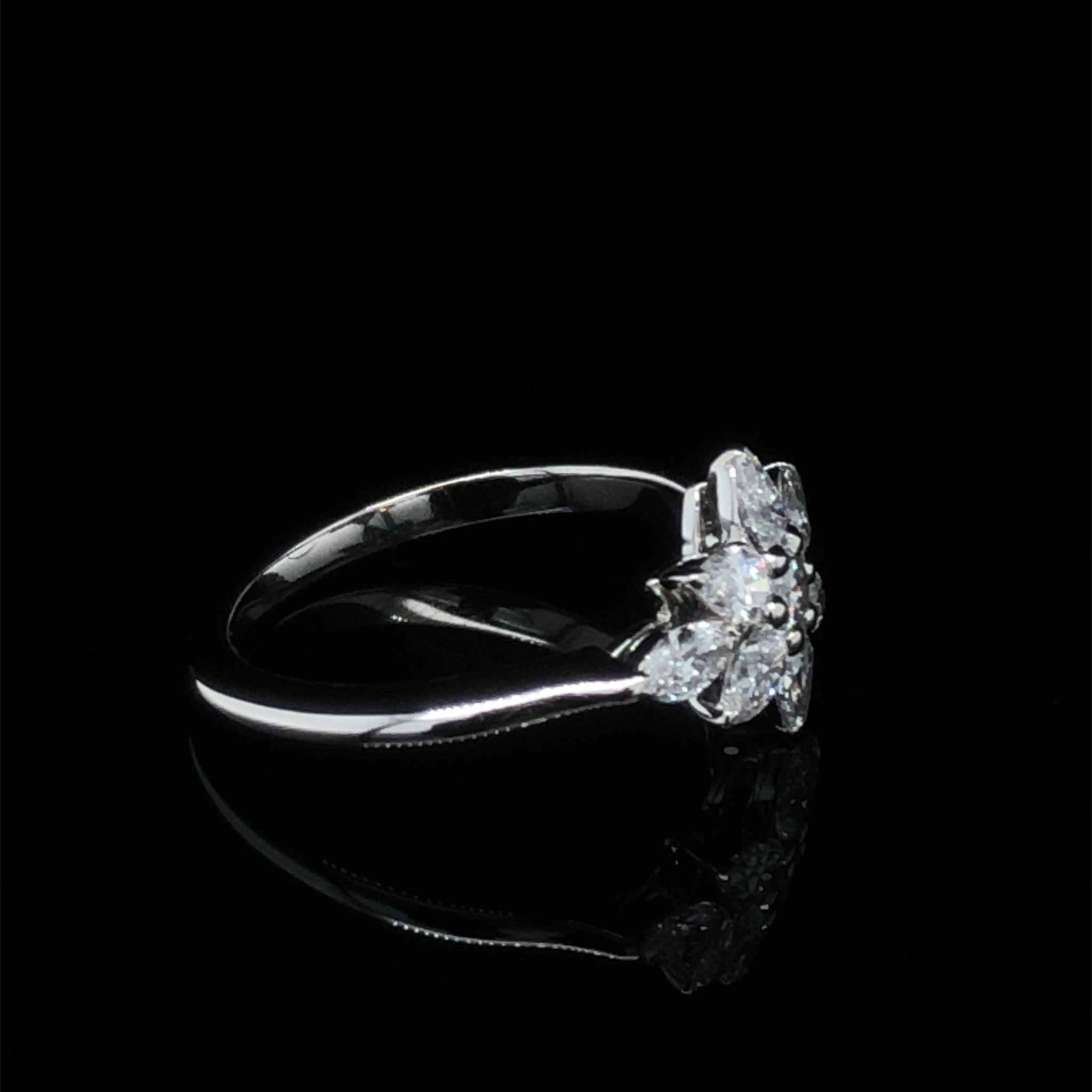 Daisy engagement ring with platinum knife-edge setting and pear, marquise, and round diamonds totaling 0.95 carats on black background