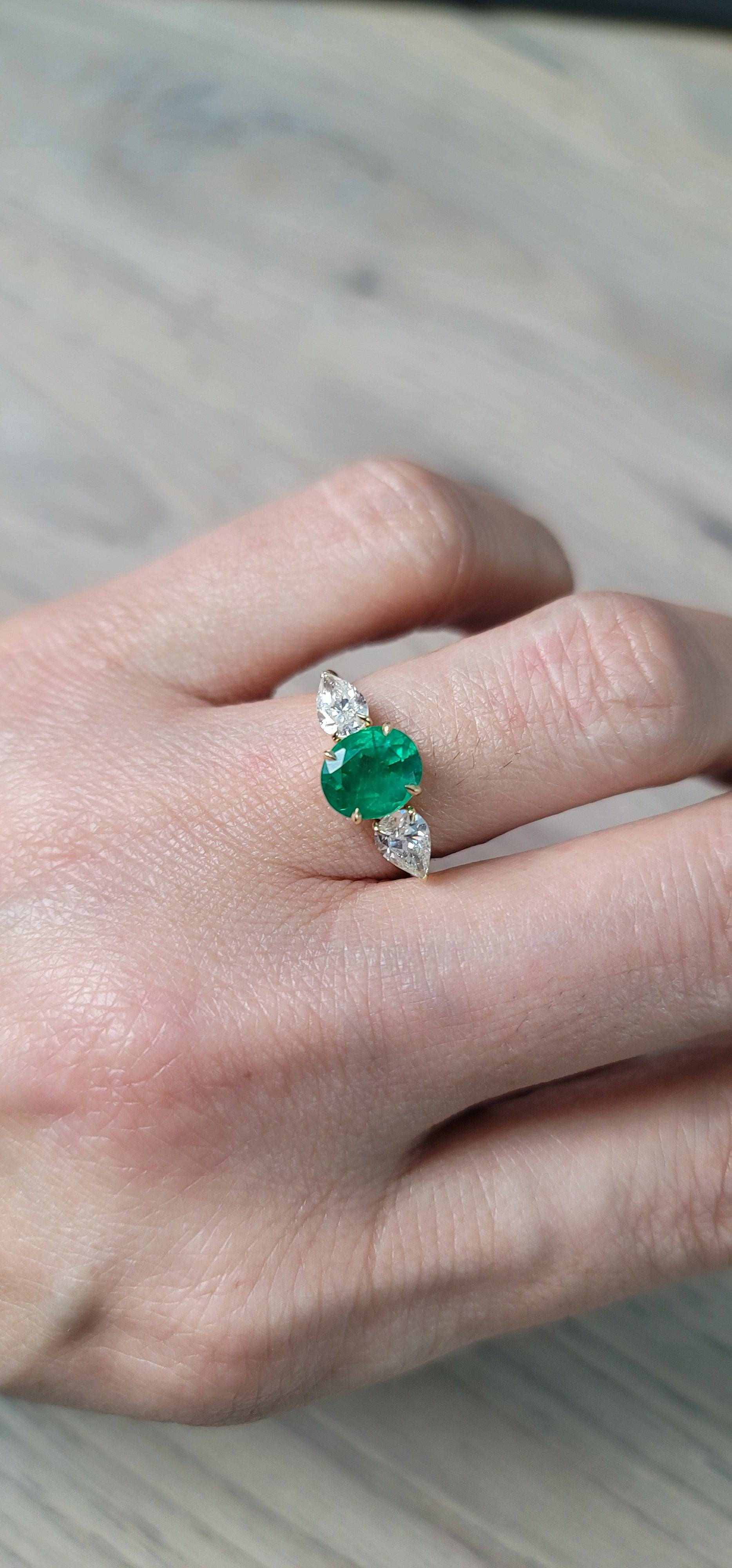 Emerald center stone engagement ring with diamond accents on hand