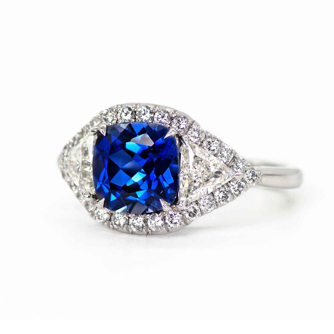 Hailey 3 Stone Halo Sapphire ring with cushion-cut blue sapphire and round diamond halo in platinum setting